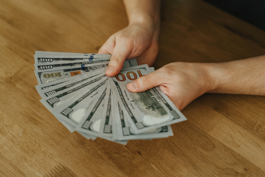 Hands fanning out a stack of one-hundred-dollar bills